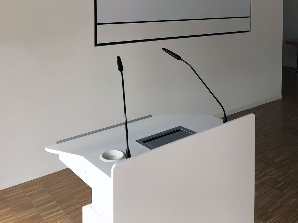 Electromotive height-adjustable lectern forum.avance in seminar room with microphones, connection panel and cable outlet